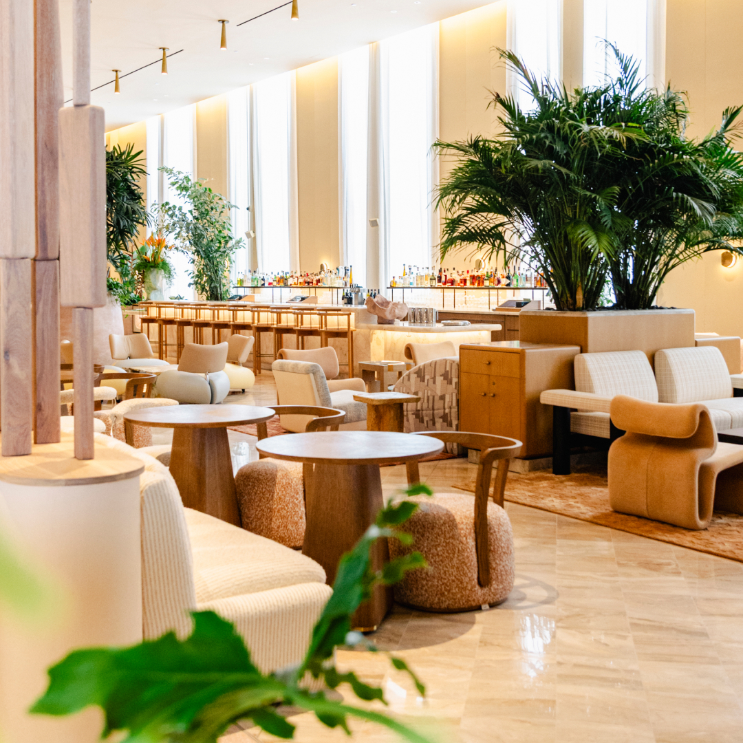 Elegant hotel lobby lounge with bar, modern seating, warm lighting, and indoor plants